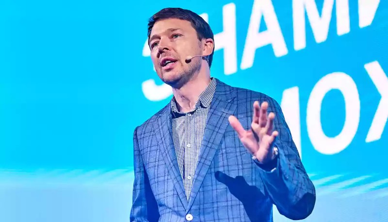 Володимир Локотко виступає на сцені з мікрофоном — публічний виступ у діловому образі.